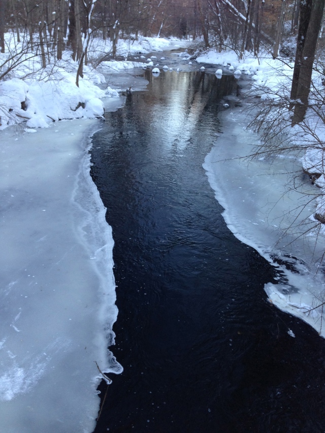 Beneath the ice, a sparkling, flowing stream.
